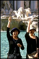 Asian tourists toss a coin over their shoulder into the Trevi Fountain. Rome, Lazio, Italy