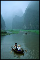 Villagers going by boat to their fields, amongst misty cliffs, Tam Coc. Ninh Binh,  Vietnam