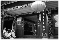 Women sit ouside  the Wufeng Lou (Five Phoenix Hall). Lijiang, Yunnan, China (black and white)