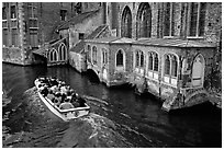 Tour boat goes by a church on a canal. Bruges, Belgium ( black and white)