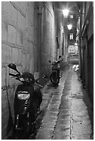 Motorcycles parked in narrow alley at night. Quartier Latin, Paris, France ( black and white)