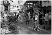Women carrying  baskets on head in narrow street, Colaba Market. Mumbai, Maharashtra, India (black and white)