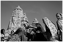 Hindu women making offerings to image with Lakshmana temple behind. Khajuraho, Madhya Pradesh, India (black and white)