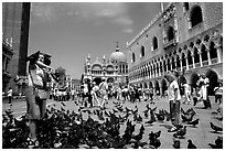 Tourists feeding  pigeons, Piazzetta San Marco (Square Saint Mark), mid-day. Venice, Veneto, Italy (black and white)