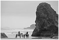 Women ridding horses next to sea stack. Bandon, Oregon, USA ( black and white)
