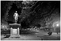 Park with statue and couples sitting on public benches at night. Charleston, South Carolina, USA ( black and white)