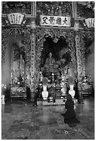 Woman praying at the altar. Ho Chi Minh City, Vietnam (black and white)