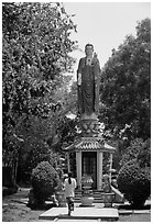 Woman praying under a large buddhist statue. Ho Chi Minh City, Vietnam (black and white)