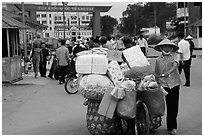 Woman pushing a bicycle loaded with cheap goods at the Lao Cai border crossing. Vietnam (black and white)