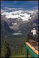 Man looking at Lake Louise through binoculars on observation platform. Banff National Park, Canadian Rockies, Alberta, Canada (color)