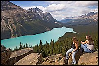 Tourists sitting on a rook overlooking Peyto Lake. Banff National Park, Canadian Rockies, Alberta, Canada