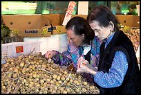 Two elderly women choosing tropical fruit. Vancouver, British Columbia, Canada
