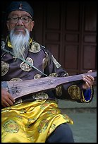 Elderly musician playing the a traditional guitar. Baisha, Yunnan, China (color)