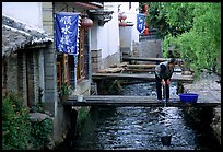 Woman fills up a water buck in the canal. Lijiang, Yunnan, China (color)