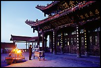 Pilgrim prays in the Jinding Si (Golden Summit) temple at dusk. Emei Shan, Sichuan, China (color)