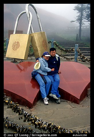Lovers sit on top of two hearts surrounded by chain locks. Emei Shan, Sichuan, China