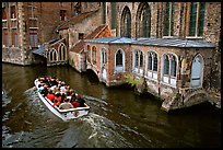 Tour boat goes by a church on a canal. Bruges, Belgium (color)