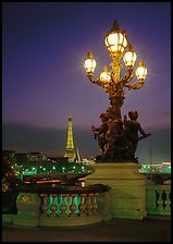 Bronze lamp post with scultpure on Pont Alexandre III, and Eiffel Tower at night. Paris, France