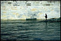 Man standing at water level fishing in the Seine River. Paris, France