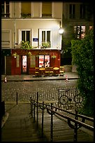 Hillside stairs on butte, street and restaurant at night, Montmartre. Paris, France
