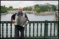 Street musician playing accordeon on River Seine bridge. Paris, France