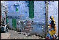 Woman walking in narrow street with blue walls. Jodhpur, Rajasthan, India