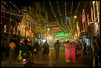 Women walking in street with illuminations. Varanasi, Uttar Pradesh, India (color)