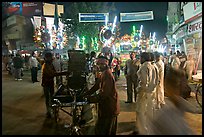 Men pulling generator on bicycle to power lights during wedding procession. Varanasi, Uttar Pradesh, India