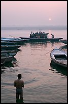 Man standing in Ganga River and boats at sunrise. Varanasi, Uttar Pradesh, India (color)