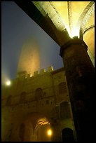 Medieval towers above Piazza del Duomo, foggy night. San Gimignano, Tuscany, Italy