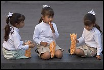 Three little girls in school uniform eating snack. Guadalajara, Jalisco, Mexico (color)