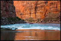 Glassy river, rapids and boat below Redwall canyon walls. Grand Canyon National Park, Arizona