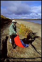 Camper folding the tarp while breaking camp. Kobuk Valley National Park, Alaska (color)