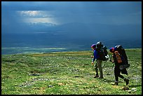 Two backpackers arrive at a ridge as a storm clears. Lake Clark National Park, Alaska