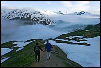 Couple hiking down Harding Icefied trail, late afternoon. Kenai Fjords National Park, Alaska, USA. (color)
