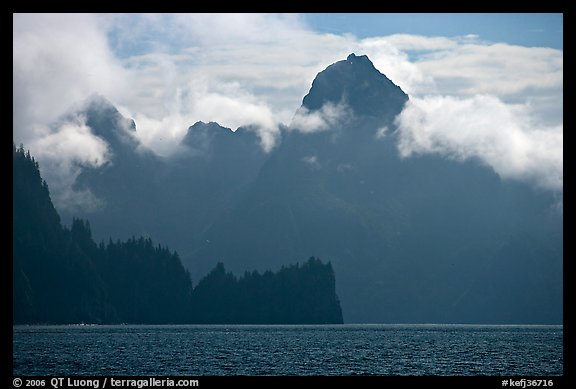 Peak emerging from the fog above bay waters. Kenai Fjords National Park, Alaska, USA.