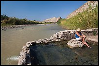 Tourist sitting in hot springs next to river. Big Bend National Park ( color)