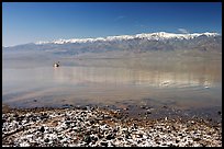 Salt formations, kayaker in a distance, and Panamint range. Death Valley National Park, California, USA.