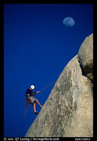 Climber rappelling down with moon. Joshua Tree National Park, California, USA.
