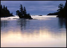 Islet and bright sky reflected in water below dark clouds. Isle Royale National Park ( color)