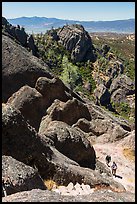 Hikers approaching cliff with steps carved in stone. Pinnacles National Park, California, USA. (color)