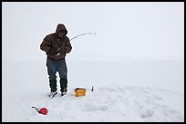 Ice fisherman standing next to hole, Jackson Lake. Grand Teton National Park, Wyoming, USA. (color)