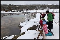 Family looks at thermal pool in winter. Yellowstone National Park, Wyoming, USA. (color)