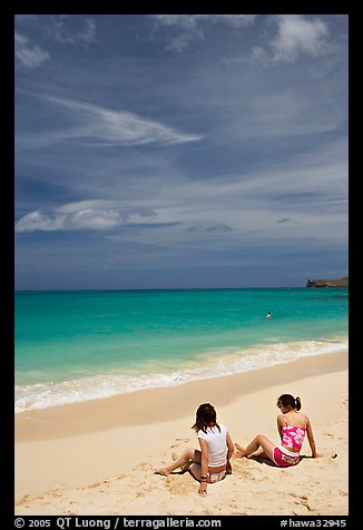 Young women sitting on Waimanalo Beach. Oahu island, Hawaii, USA