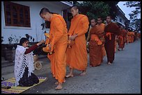 Buddhist monks receiving alm from woman. Luang Prabang, Laos (color)