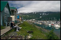 Couple sitting on bench by the harbor. Whittier, Alaska, USA ( color)