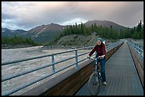 Woman on mountain bike crossing the footbridge. McCarthy, Alaska, USA