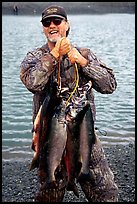 Man carrying salmon freshly caught in the Fishing Hole. Homer, Alaska, USA (color)