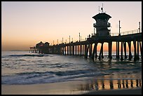 The 1853 ft Huntington Pier reflected in wet sand at sunset. Huntington Beach, Orange County, California, USA