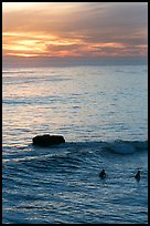 Surfers and rock at sunset. Santa Cruz, California, USA